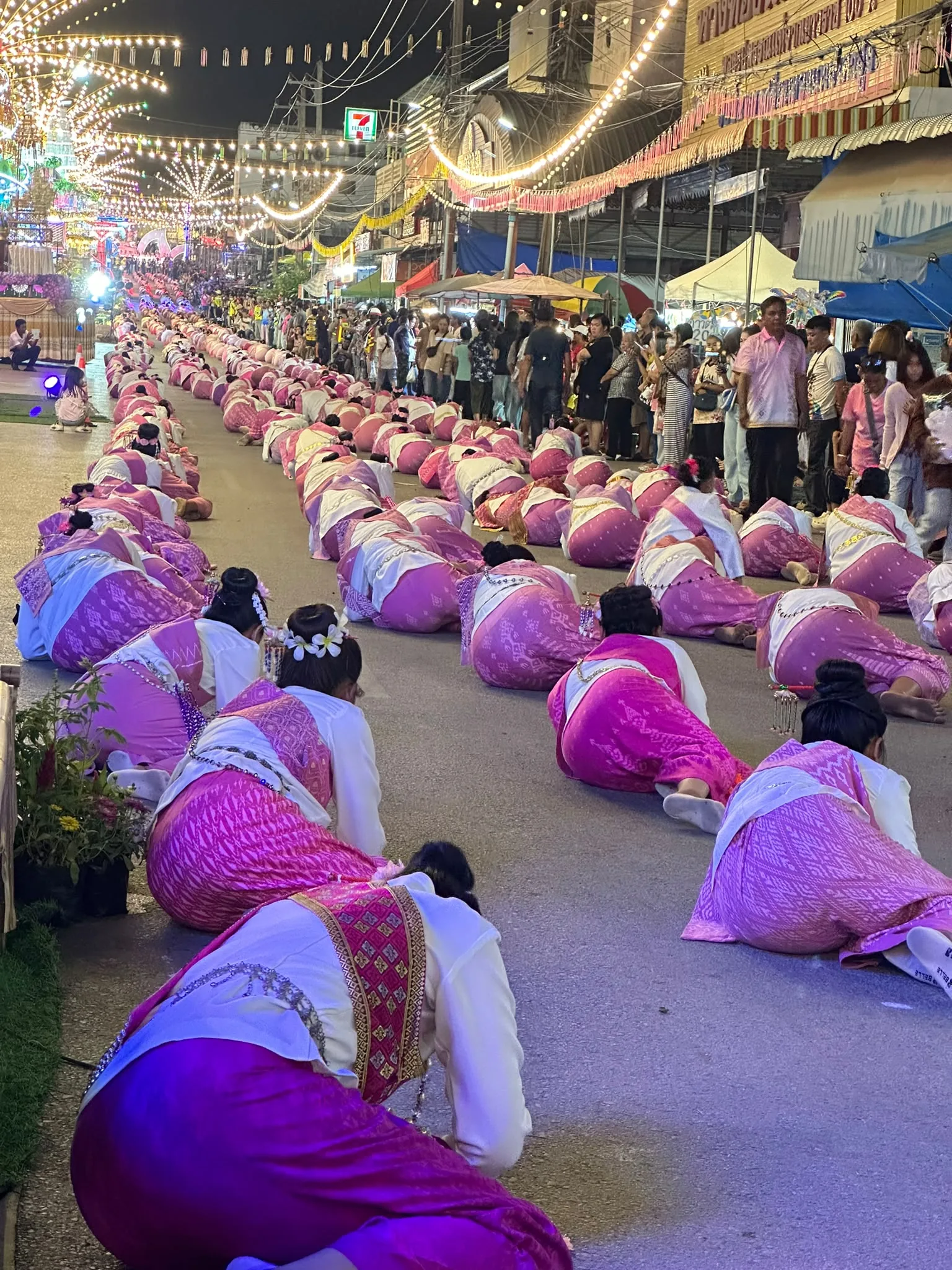 The procession pauses and the dancers bow in the road